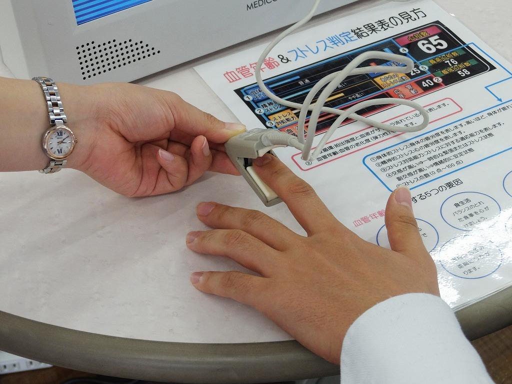 血管年齢測定のセンサーを指に取り付ける写真