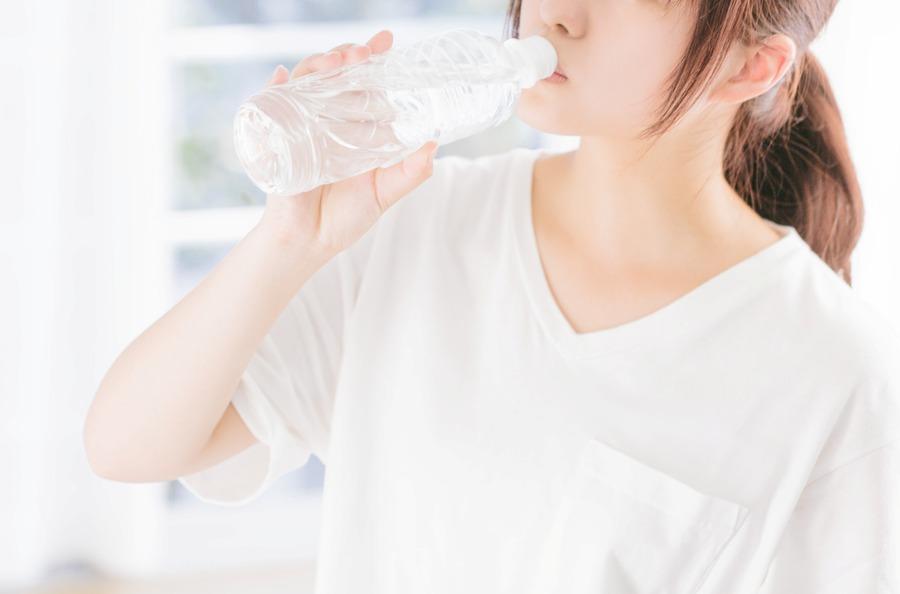 ペットボトルの水を飲む女性