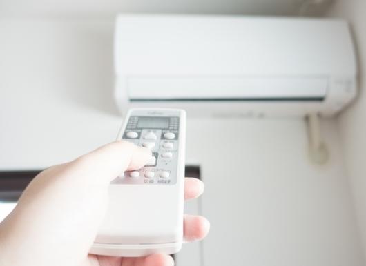 リモコンでエアコンの温度調整をしている様子