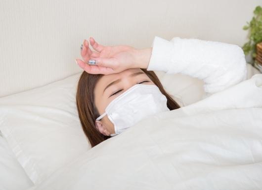 マスク姿で寝込む女性