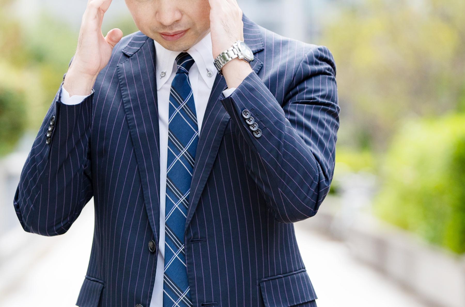 頭を抱えるスーツの男性