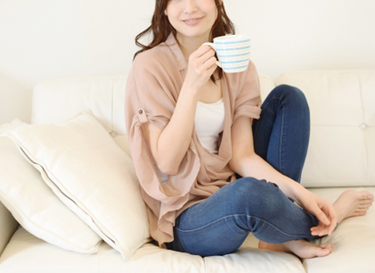 ソファでコーヒーを飲む女性