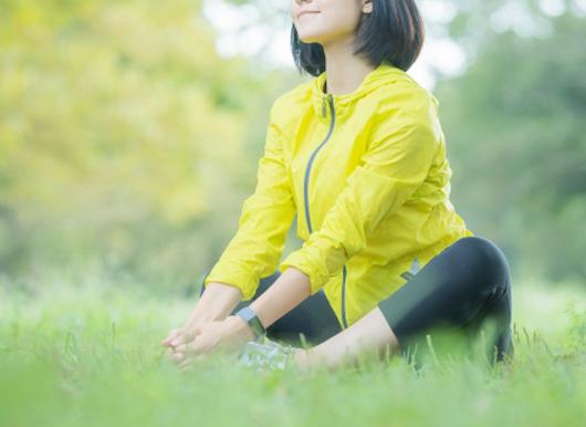 草むらでストレッチする女性