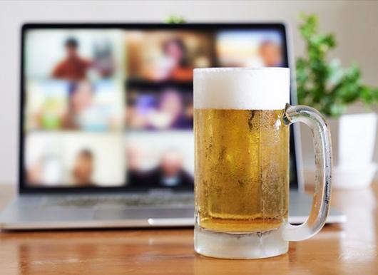 オンライン飲み会を写すタブレットとジョッキに入ったビール