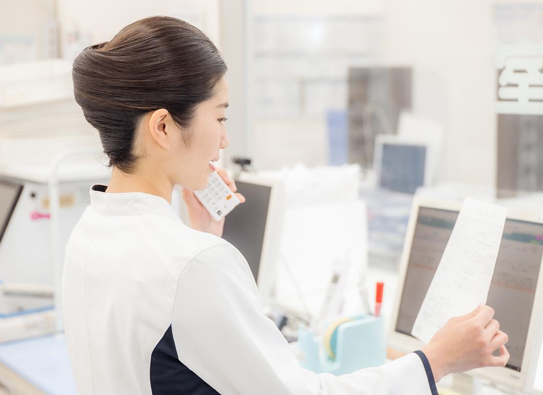 資料を見ながら電話する薬剤師