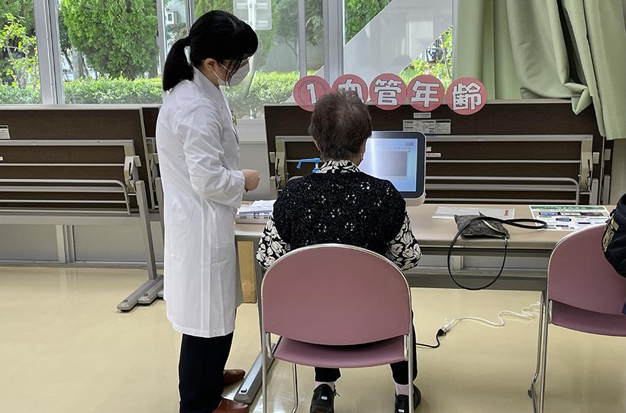 患者さまに血管年齢測定を行う薬剤師