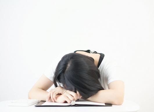 机の上で伏せる女性