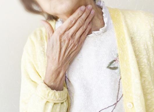 右手を喉に当てる高齢女性