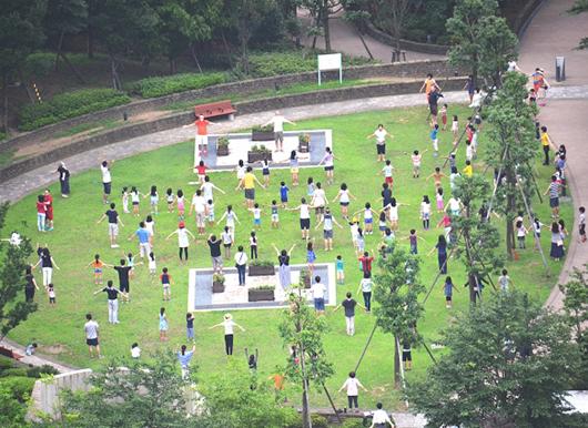 公園でラジオ体操をする大勢の人々