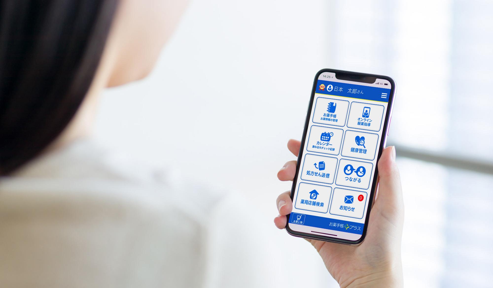 手にしたスマホに表示される、日本調剤の電子お薬手帳「お薬手帳プラス」のトップ画面