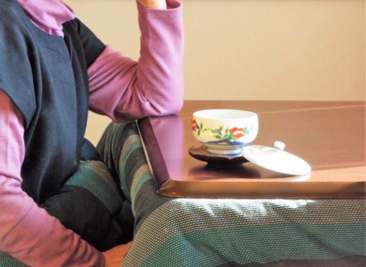 こたつに入ってお茶を飲んでいる女性