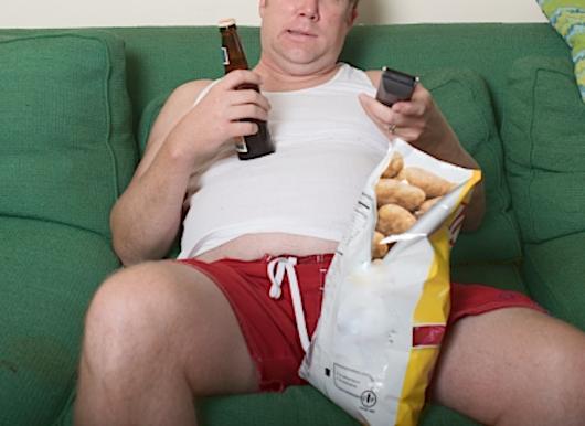 ソファで間食やお酒を摂ってだらだら過ごしている男性