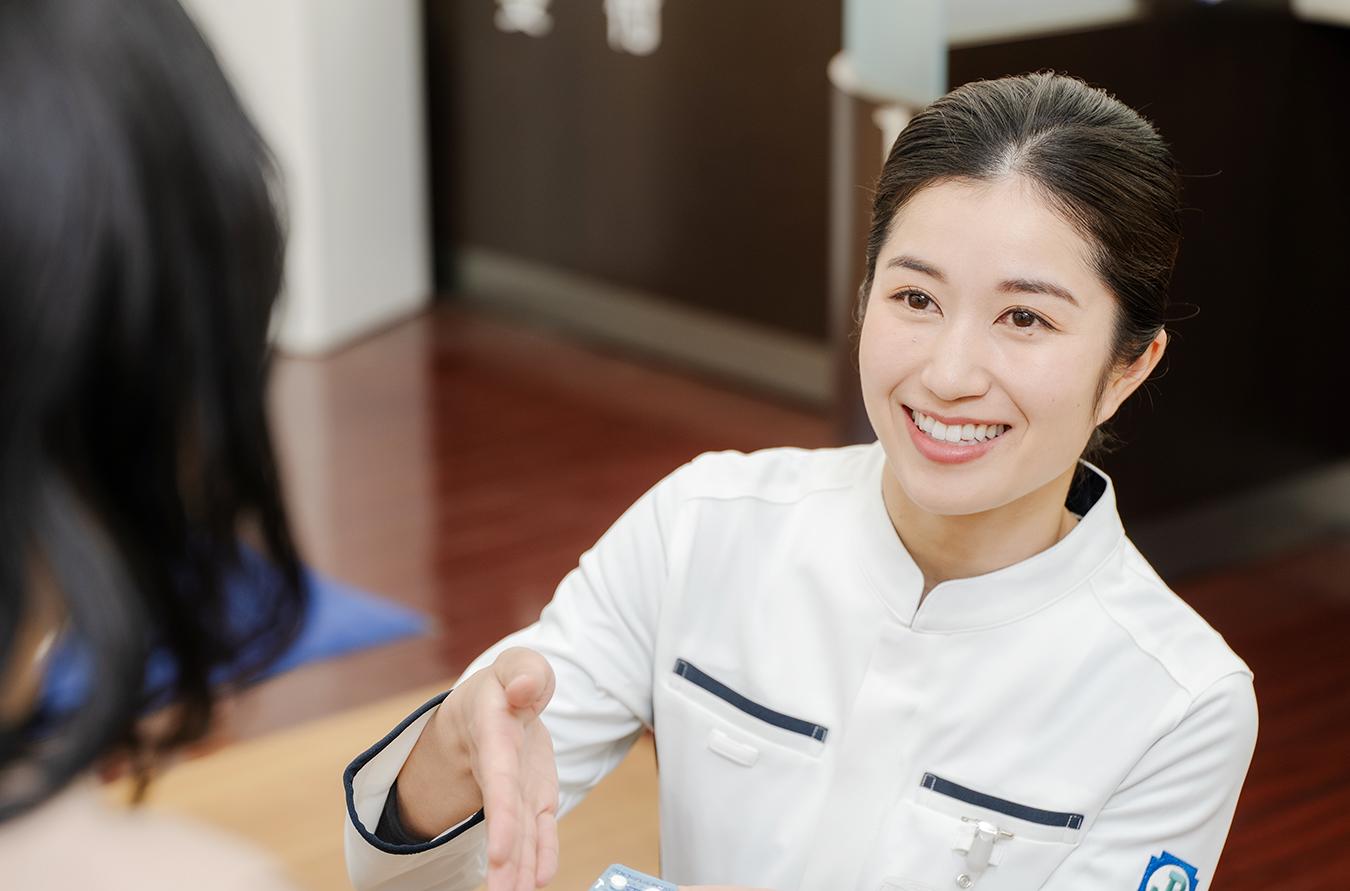 待合席に座っている患者さまに向かい、腰を落としてご案内する薬剤師